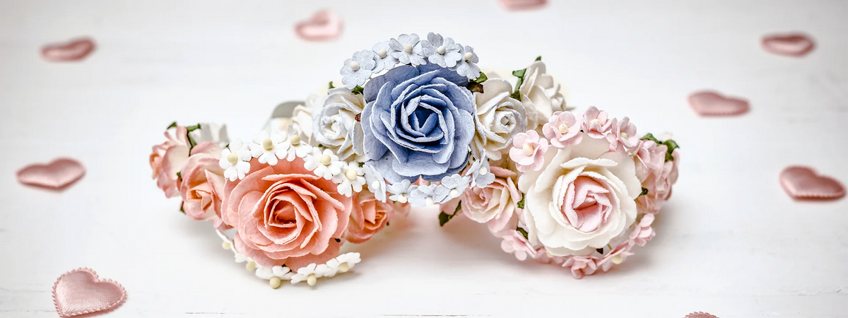 Drei Hope22 Blumenarmbänder mit Rosen in Rosé, Blau und Creme auf hellem Holz mit Herzdeko – Armbänder für JGA und Hochzeit