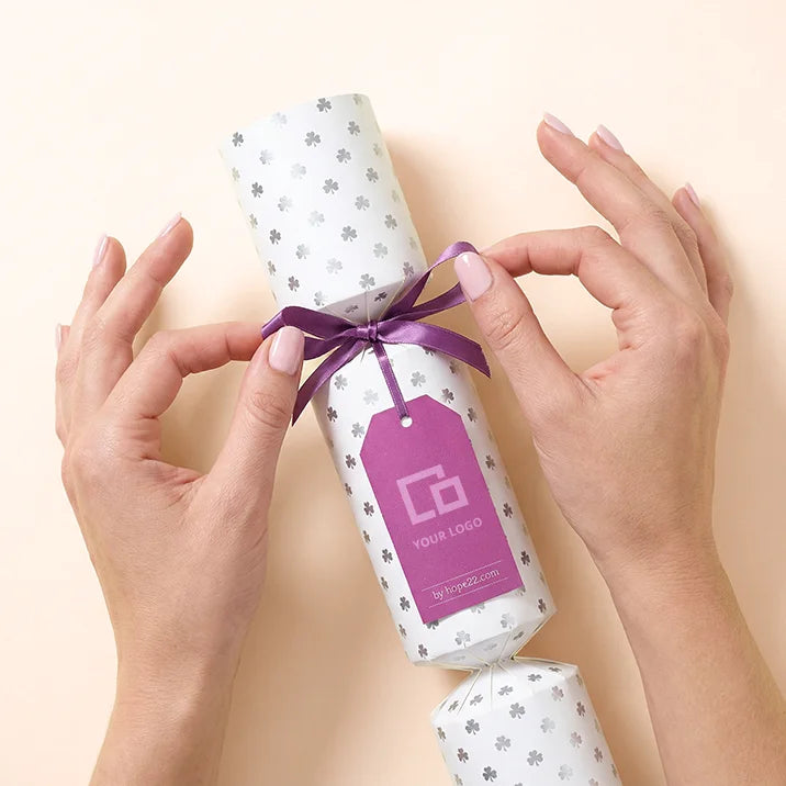 Hände binden ein Hope22 Knallbonbon mit individuellem Logo-Anhänger – personalisierbares Firmengeschenk
